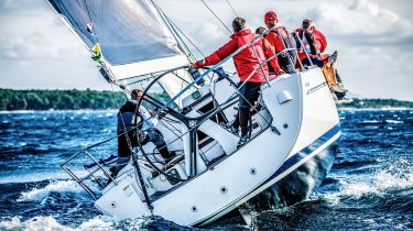 L'équipage d'un voilier masculin vêtu de rouge navigue sur une mer agitée.